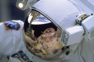 Spejling af jorden i astronauts hjelm med skærm belagt af guld